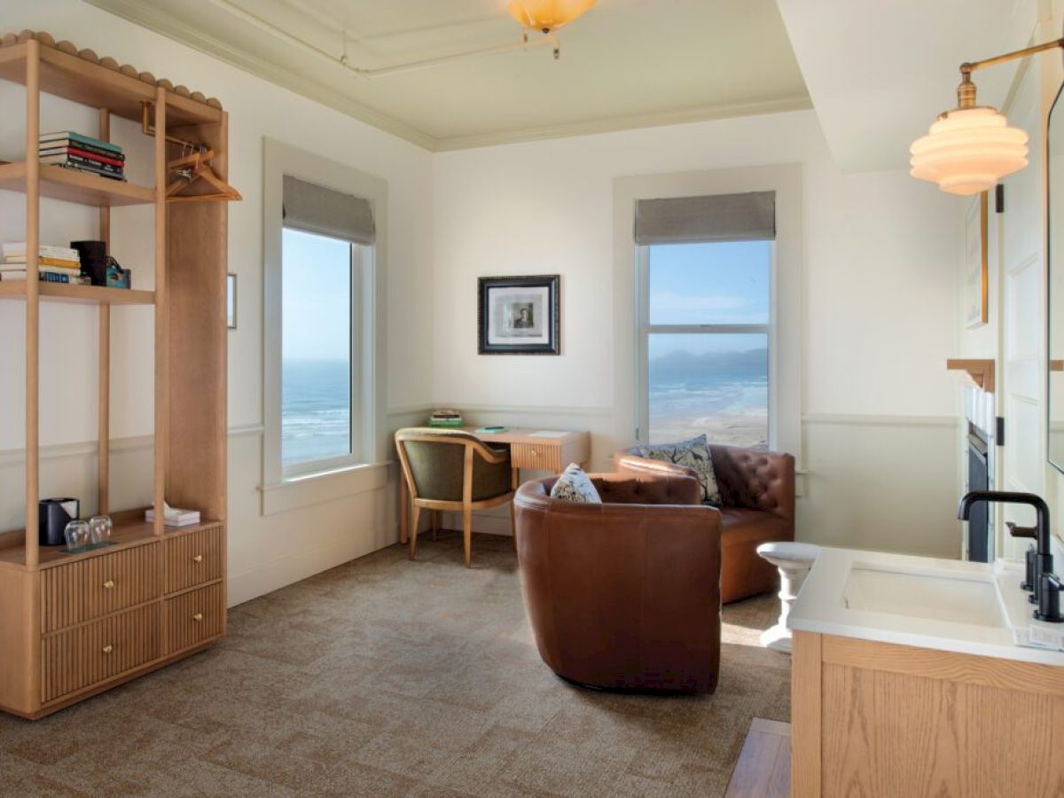 A cozy room with a sea view features a wooden shelf, leather chair, desk, and a small sink area.
