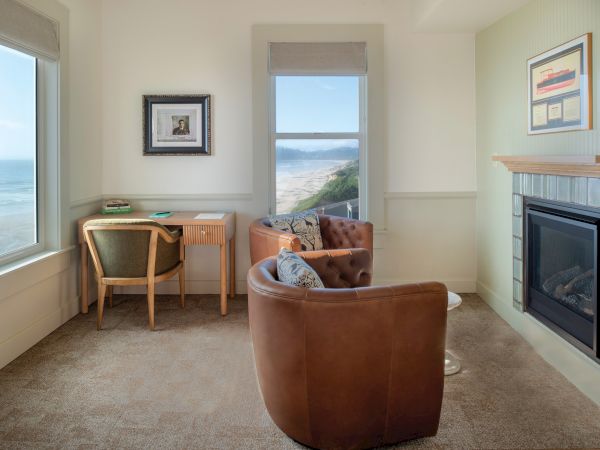 A cozy room with ocean views, featuring a desk, chairs, fireplace, and framed art on the walls, creating a relaxing atmosphere.