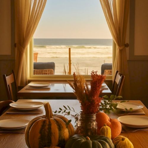 A cozy dining table indoors with a fall harvest centerpiece of pumpkins and gourds, window-view of the seashore and soft curtains framing the scene.